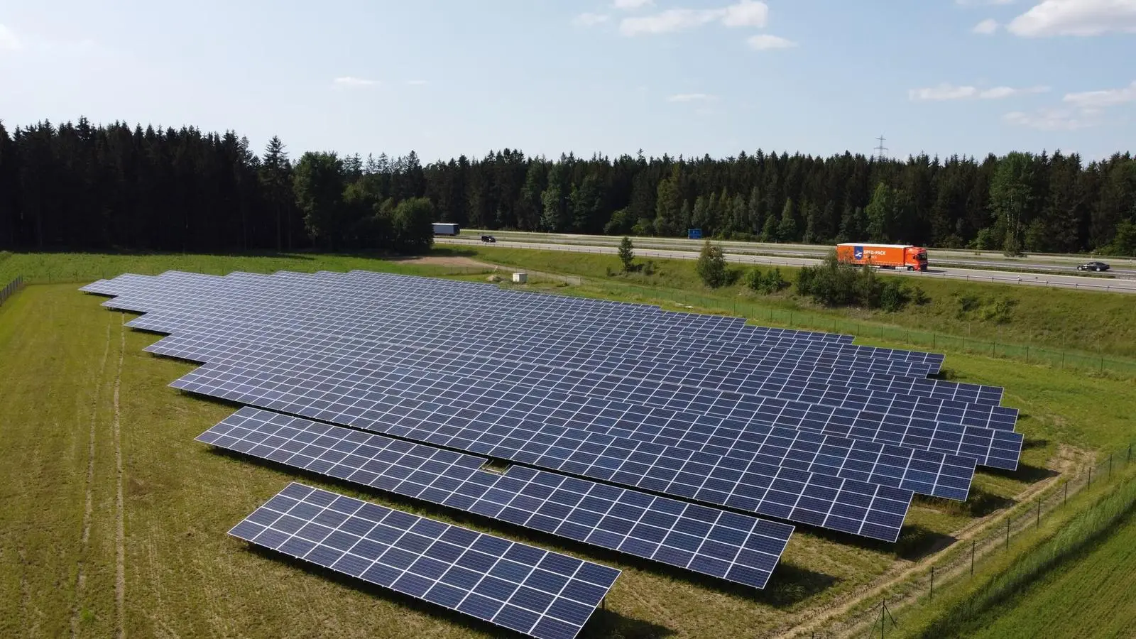 Freiflächenanlage vor Waldkulisse, im Hintergrund die Autobahn