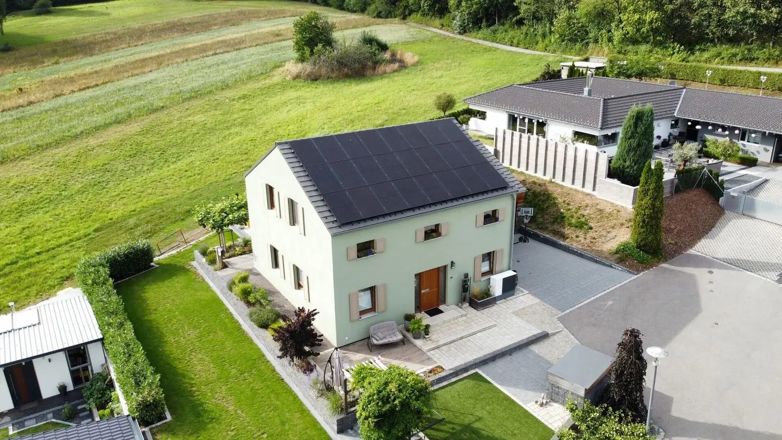 Einfamilienhaus mit schwarzen Modulen auf dem Satteldach, Luftaufnahme