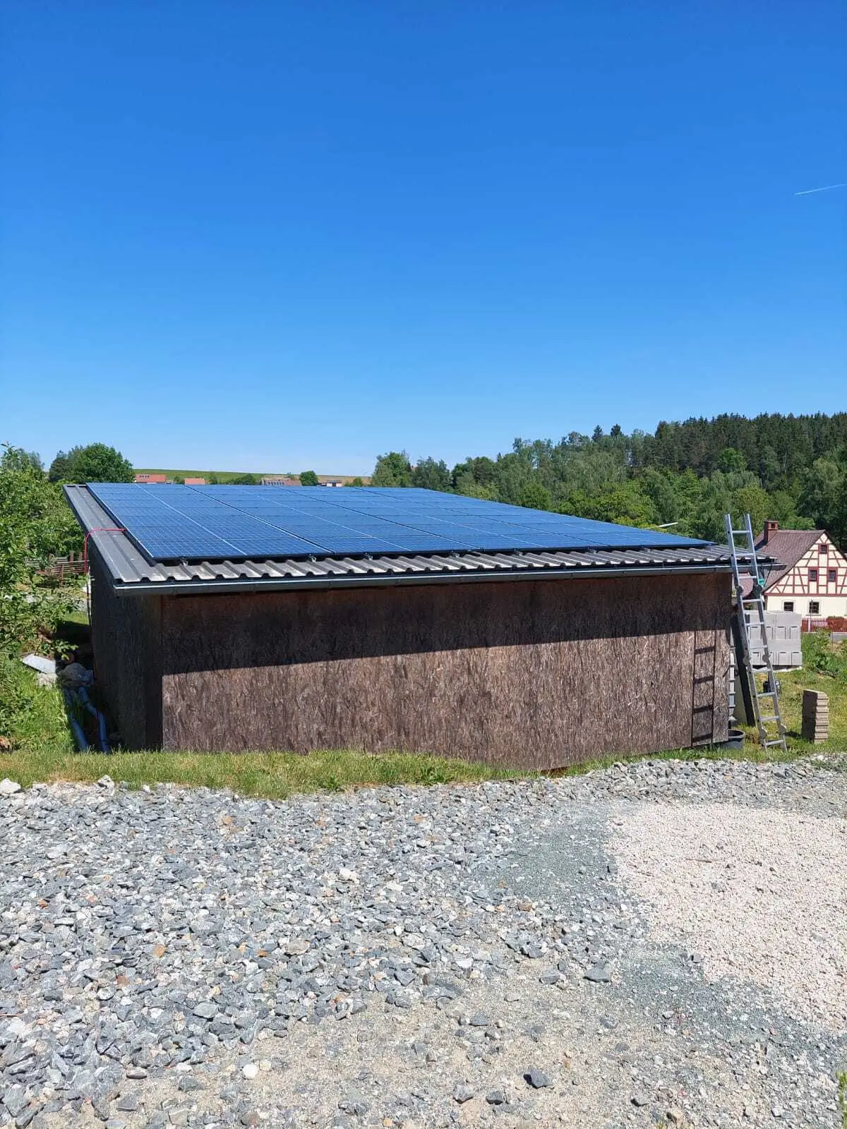 Carport mit dunkler Holzverkleidung und Photovoltaikdach