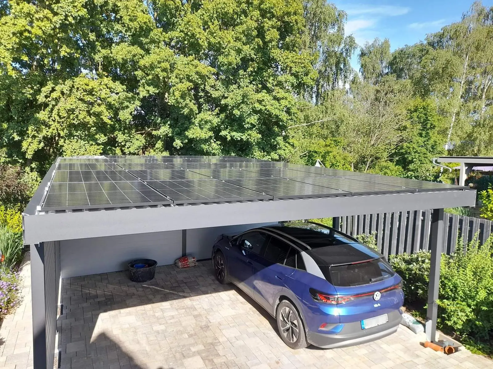 Carport mit Photovoltaikdach, darunter ein Elektroauto