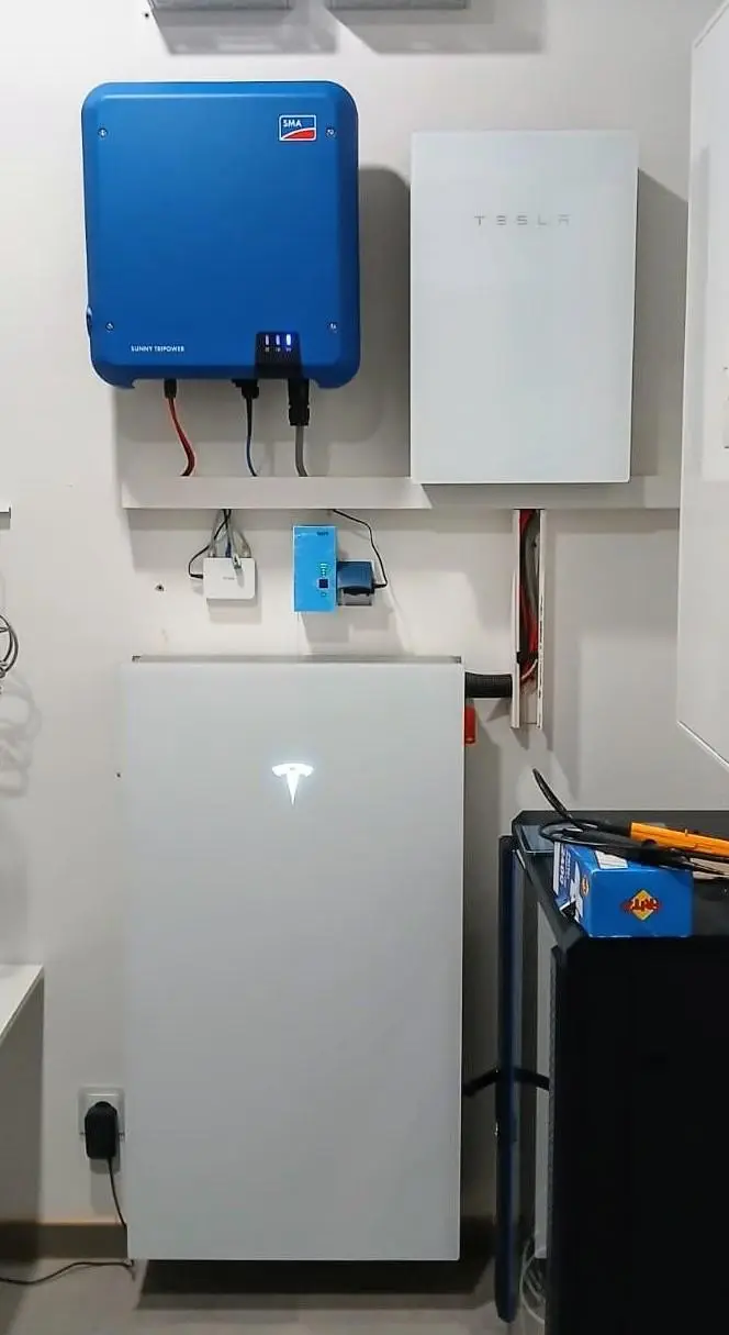 Tesla Powerwall 3 mit Gateway, daneben ein Wechselrichter an der Technikwand
